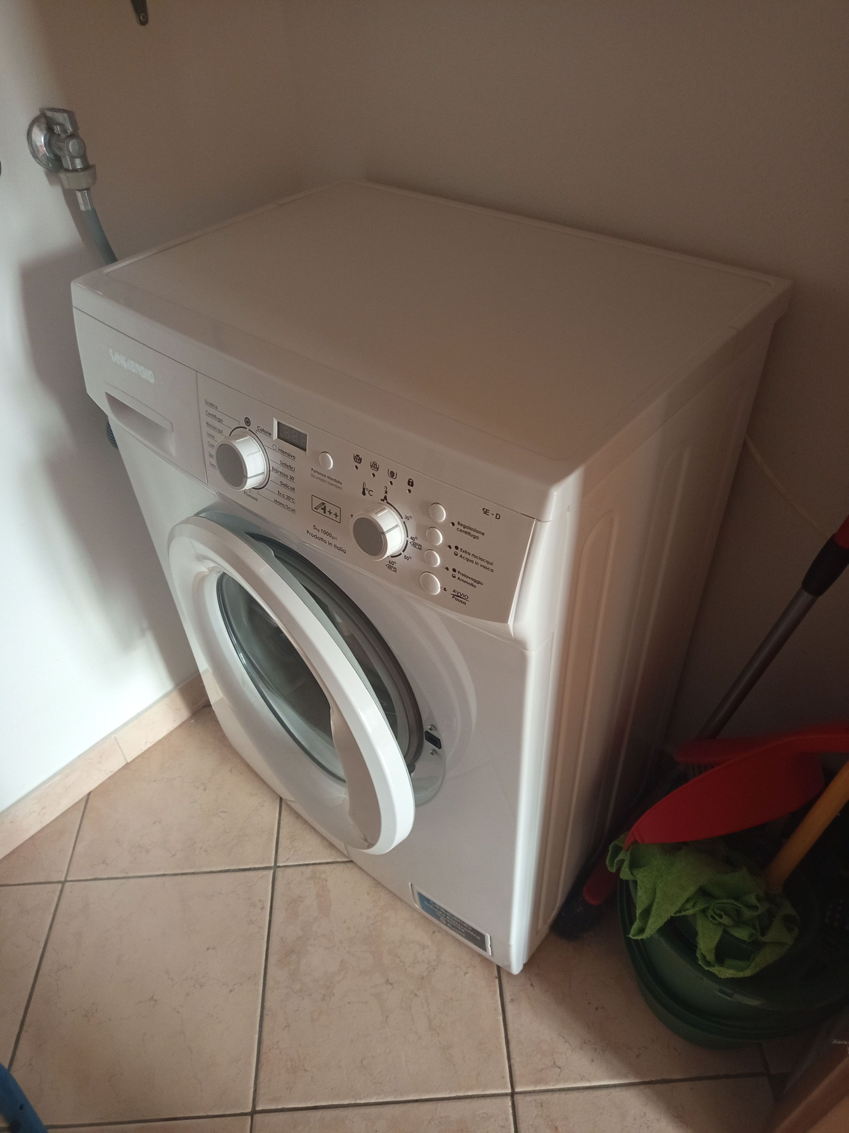 Eine Waschmaschine mit Frontlader in einem Waschraum mit Fliesenboden.