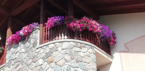 Een stenen balustrade met houten leuning en kleurrijke bloemen.