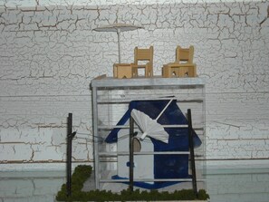 Een model van een gebouw met een raam, een blauw-wit interieur en een klein groen gebied aan de onderkant.