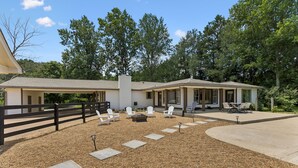 A two-story house with a covered patio area, outdoor seating, and a fire pit.