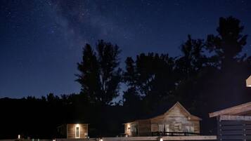 Un ciel étoilé, une cabane en bois et un jardin clos.