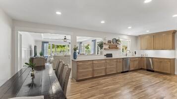 Une cuisine moderne avec des meubles en bois, un îlot central et un coin repas comprenant une table et des chaises en bois foncé.