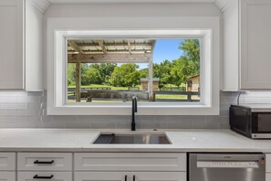 A kitchen with a built-in sink, a Bosch dishwasher, and a window overlooking a park.