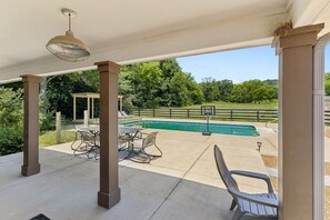 Un patio couvert avec une piscine, du mobilier d’extérieur et une vue sur le paysage environnant.
