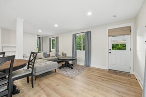 A modern interior with a dining area, a sofa set, and a door with a window view.