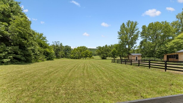 A grassy field with a wooden fence and a small wooden structure.