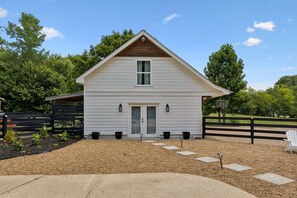 A two-story white house with a front porch, a wooden fence, and a basketball hoop.