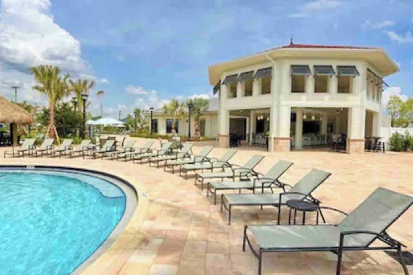 Ein Swimmingpool mit Liegestühlen und ein Gebäude mit rotem Dach.
