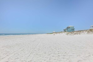 A beach with a single light blue building on a dune, a clear sky, and a sandy beach. - Read  the Reviews!Right on the Beach with East and West Views! Cannot get any closer to the Water! (Orange Beach)