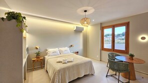 A bedroom with a bed, bedside tables, a small round table with a chair, a window with a view, and a hanging plant. - Vrbo Property (Pirenópolis)