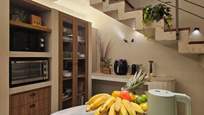 Una cocina con horno empotrado, cafetera y frutero sobre la encimera.