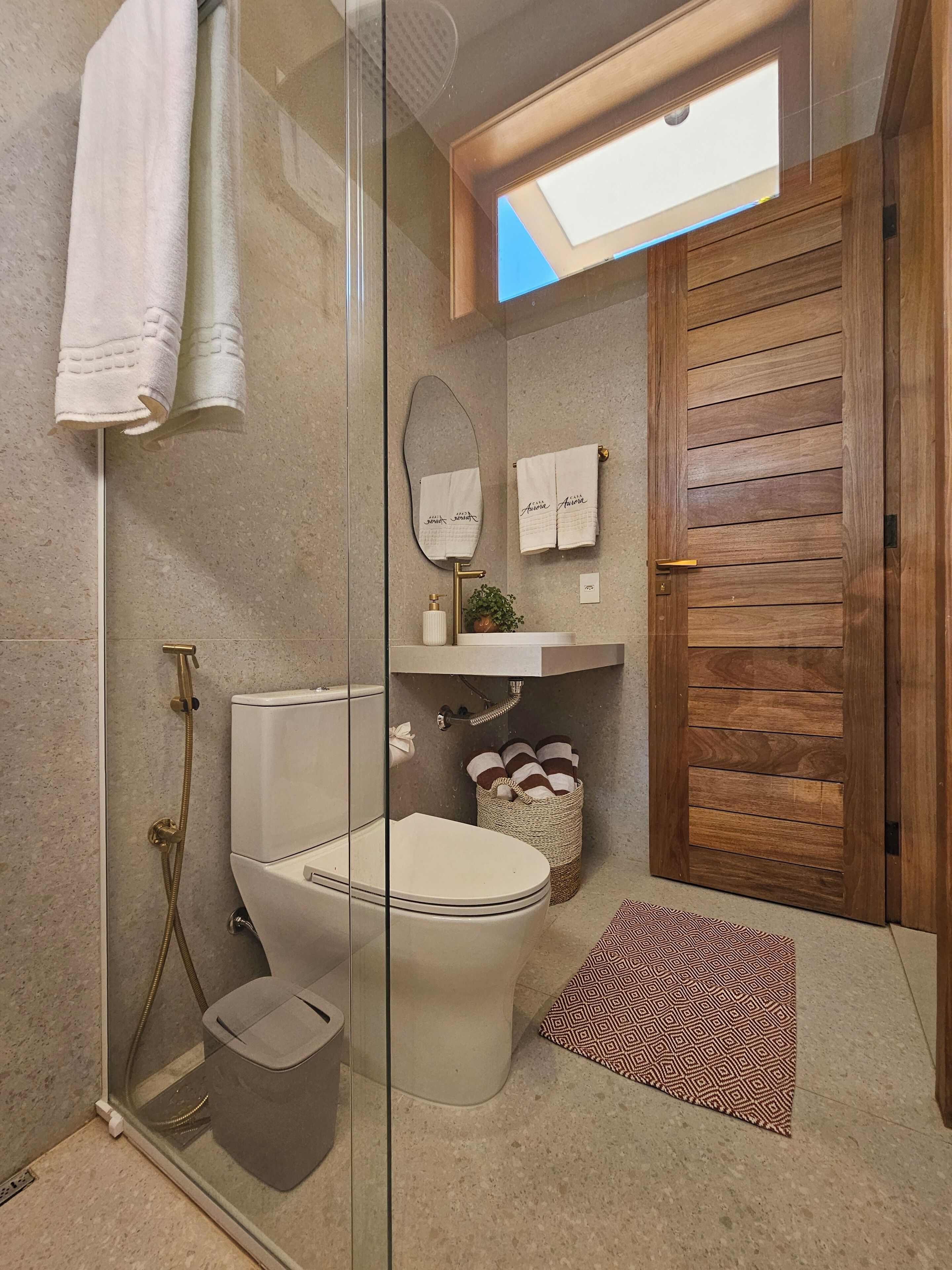 Un bagno con doccia vetrata, un WC, un lavandino con specchio e una porta in legno.