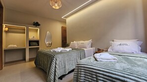 A hotel room with two beds, a large mirror, a shelf with towels, and a small plant. - Vrbo Property (Pirenópolis)