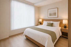 Ein Hotelzimmer mit großem Fenster, einem Bett mit weißer Bettwäsche und einer grünen Decke, zwei Nachttischen mit Lampen und einem gerahmten Bild an der Wand.
