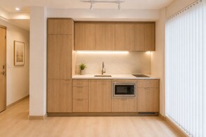 Eine moderne Küche mit Holzausstattung, einer eingebauten Mikrowelle und einer kleinen Arbeitsfläche.