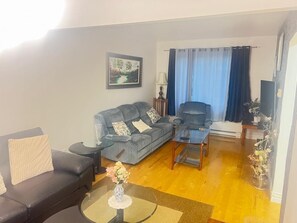 Una sala de estar con un sofá, un sillón, una mesa de centro y un cuadro en la pared.