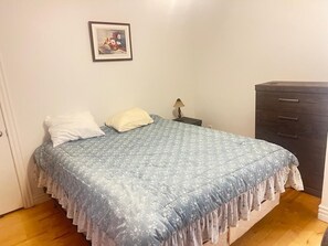 Un dormitorio con una cama, una mesita de noche, un aparador y un cuadro en la pared.