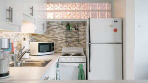 A compact kitchen with a microwave, stove, and refrigerator. - Whimsical mid-century mod at famed Ocotillo Lodge (Palm Springs)