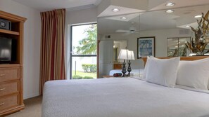 Een hotelkamer met een groot bed, een televisie op een houten kast, een bureau met een lamp en uitzicht op de omgeving.