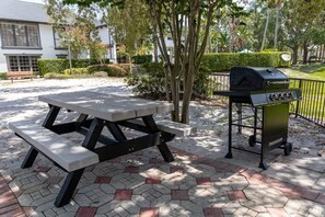 Een terras buiten met een picknicktafel en een draagbare grill.