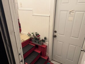 A narrow stairway leading to a white door with a metal handle.