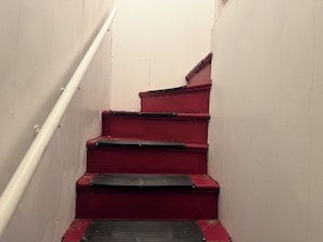 A set of red stairs with a handrail on the left, leading to a higher floor.