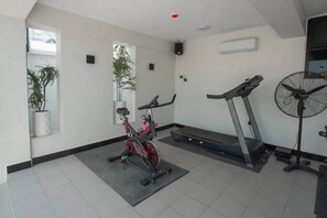 A gym with exercise equipment including a stationary bike, treadmill, and fan. - New Modern Bliss apt- 3Bdrm w/pool- gym-hottub (Dar es Salaam)