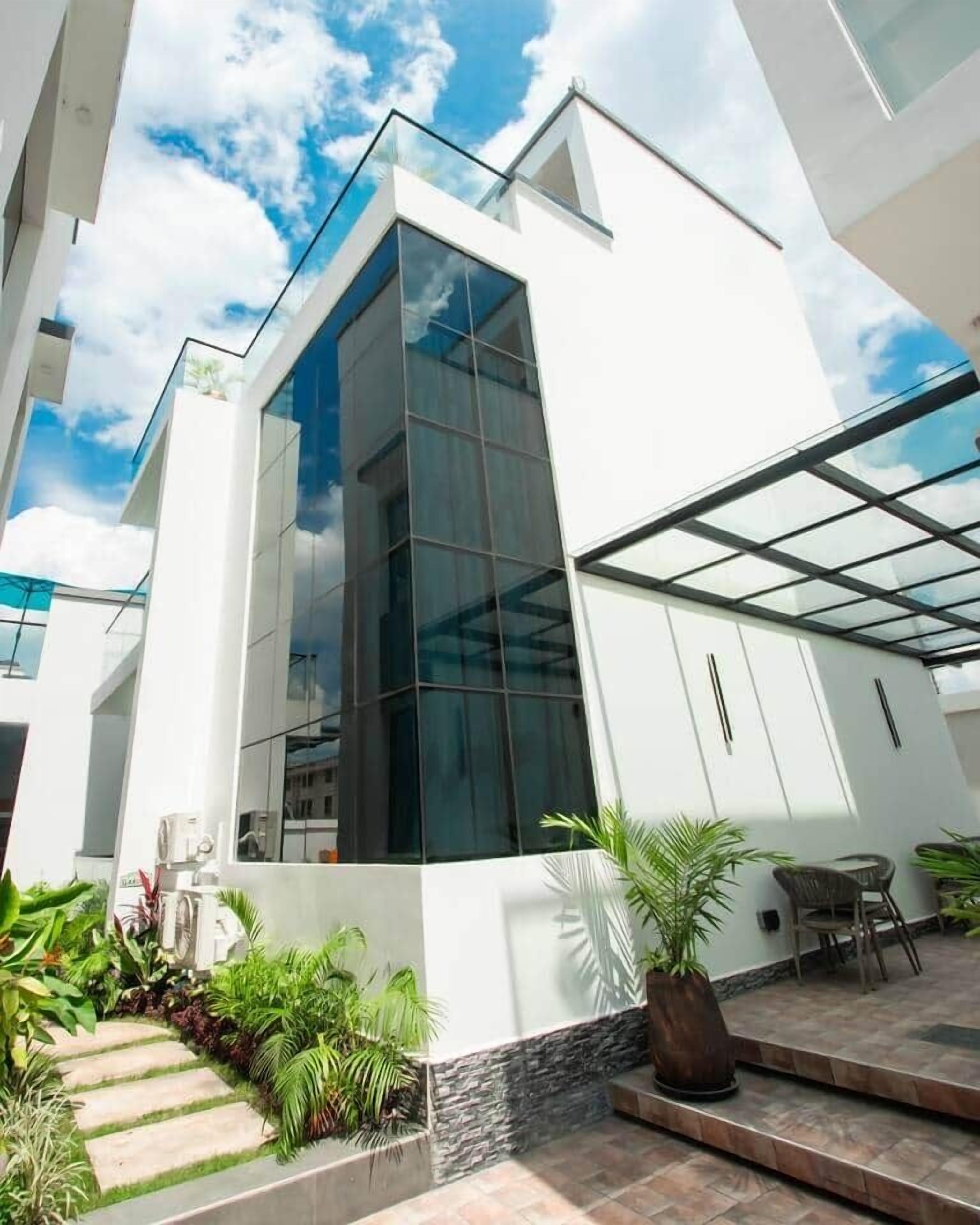 A modern building with a glass facade, outdoor seating, and a landscaped area with plants.