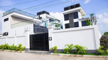 A modern two-story residential building with a black gate, number 9, and a balcony with a railing.