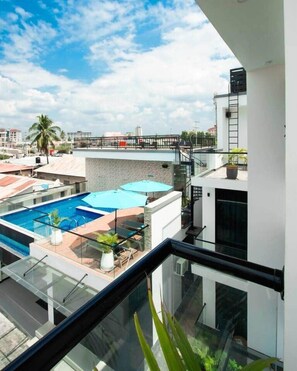 A rooftop pool area with glass railings, a ladder, and a view of the cityscape. - Luxury Oasis 2BDR Apt. w/POOL - Jacuzzi - Gym - Near Mall (Dar es Salaam)