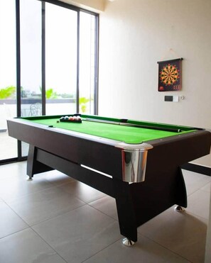 Ein Billardtisch mit Kugeln, eine Dartscheibe und ein Lichtschalter an der Wand.