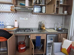A compact kitchenette with a microwave, gas stove, and a small refrigerator. - The Sunrise Apt |Balcony view | Wi- FI | Near town (Dar es Salaam)