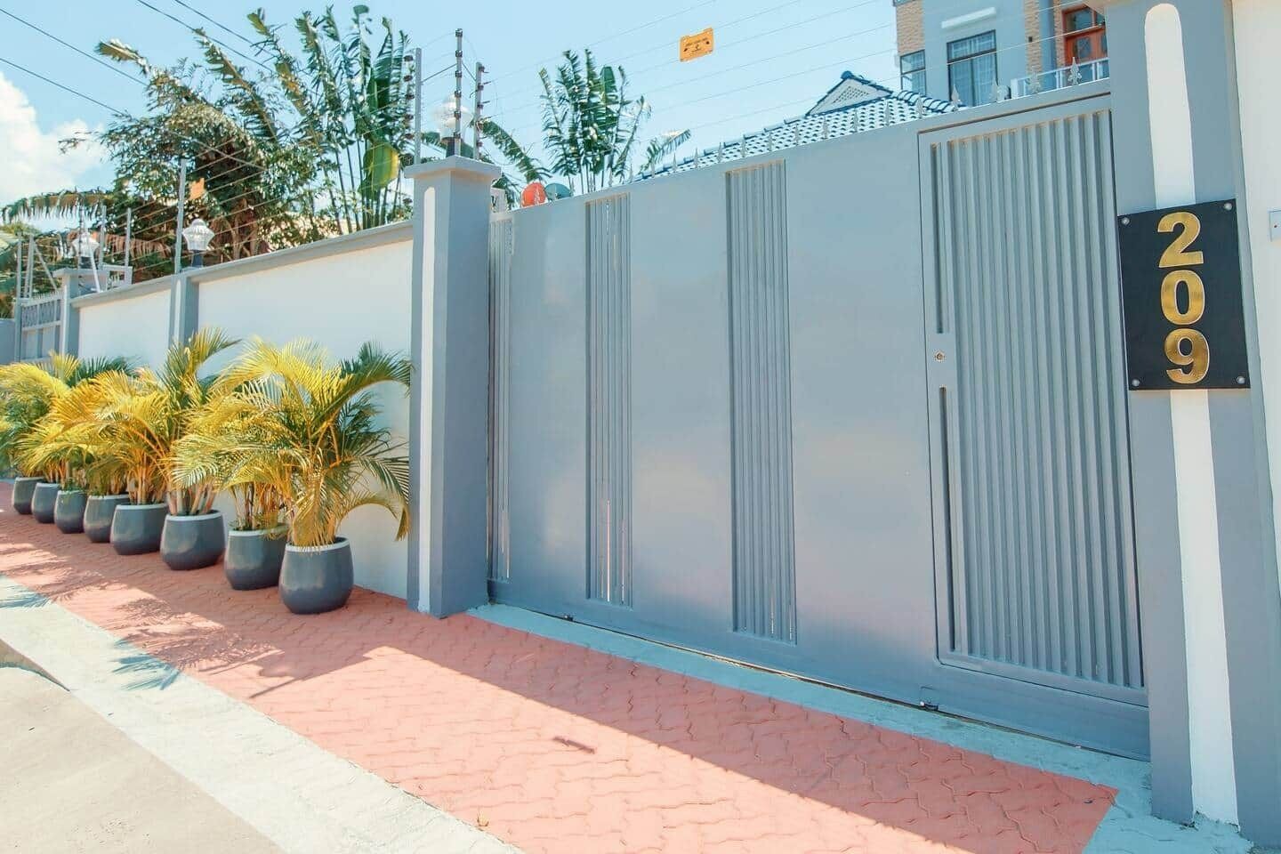 A gated property with a number sign, potted plants, and a paved walkway.