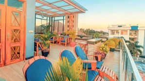 En tagterrasse med udendørs siddepladser, plantekasser og frit udsyn til de omkringliggende bygninger.