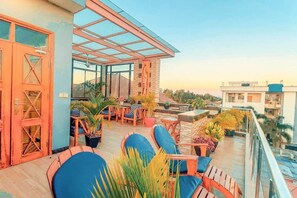 Une terrasse sur le toit, aménagée avec des espaces de détente en plein air, des plantes en pot et offrant une vue dégagée sur les bâtiments environnants.