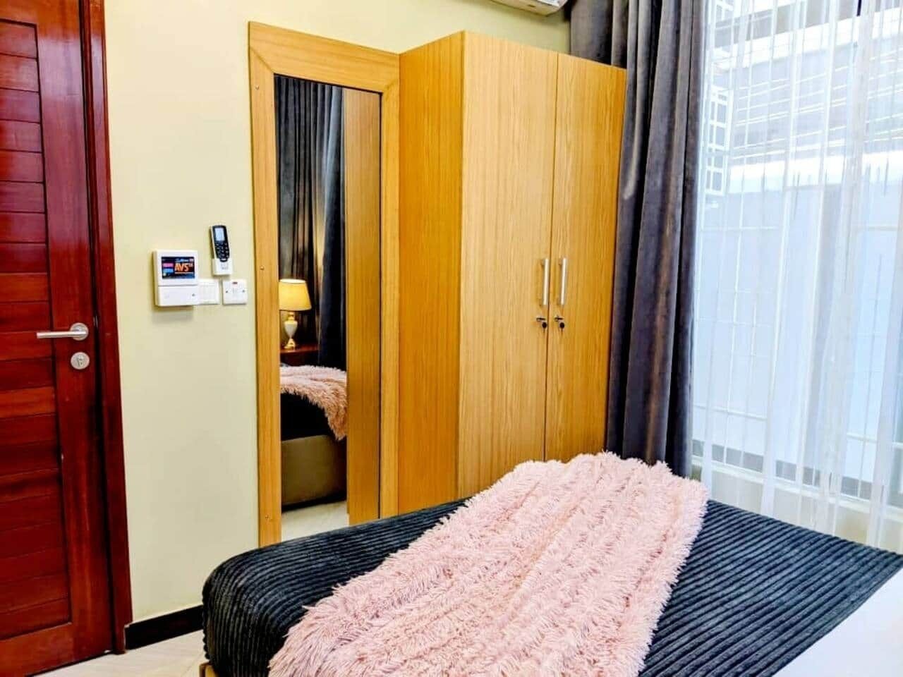 A bedroom with a bed, a wardrobe, and a mirror.
