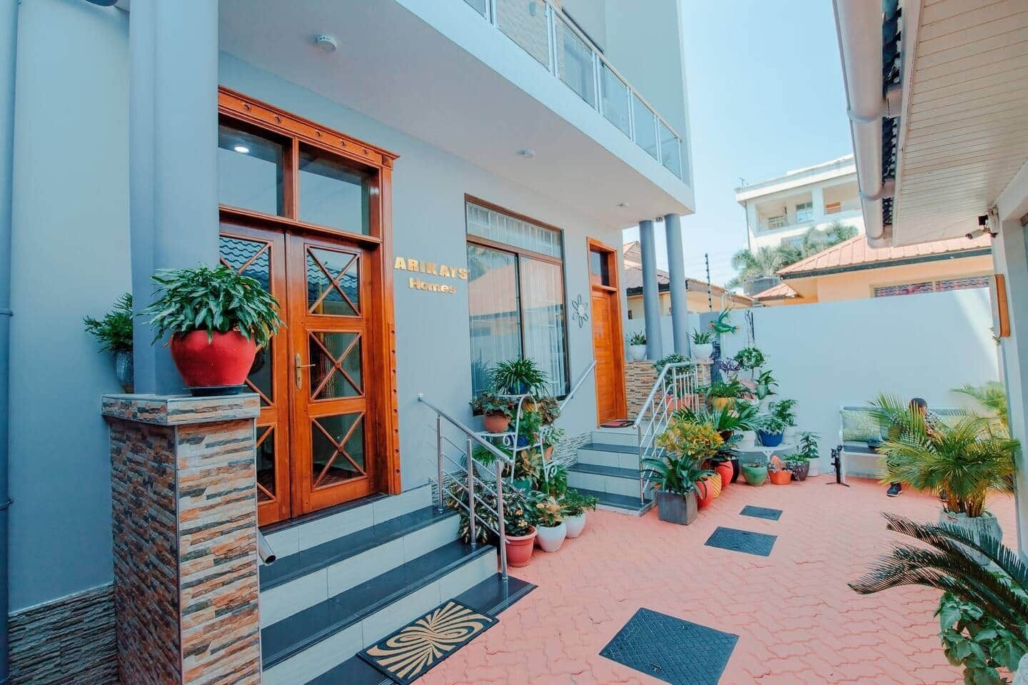 A hotel entrance with a wooden door, a staircase, and potted plants.