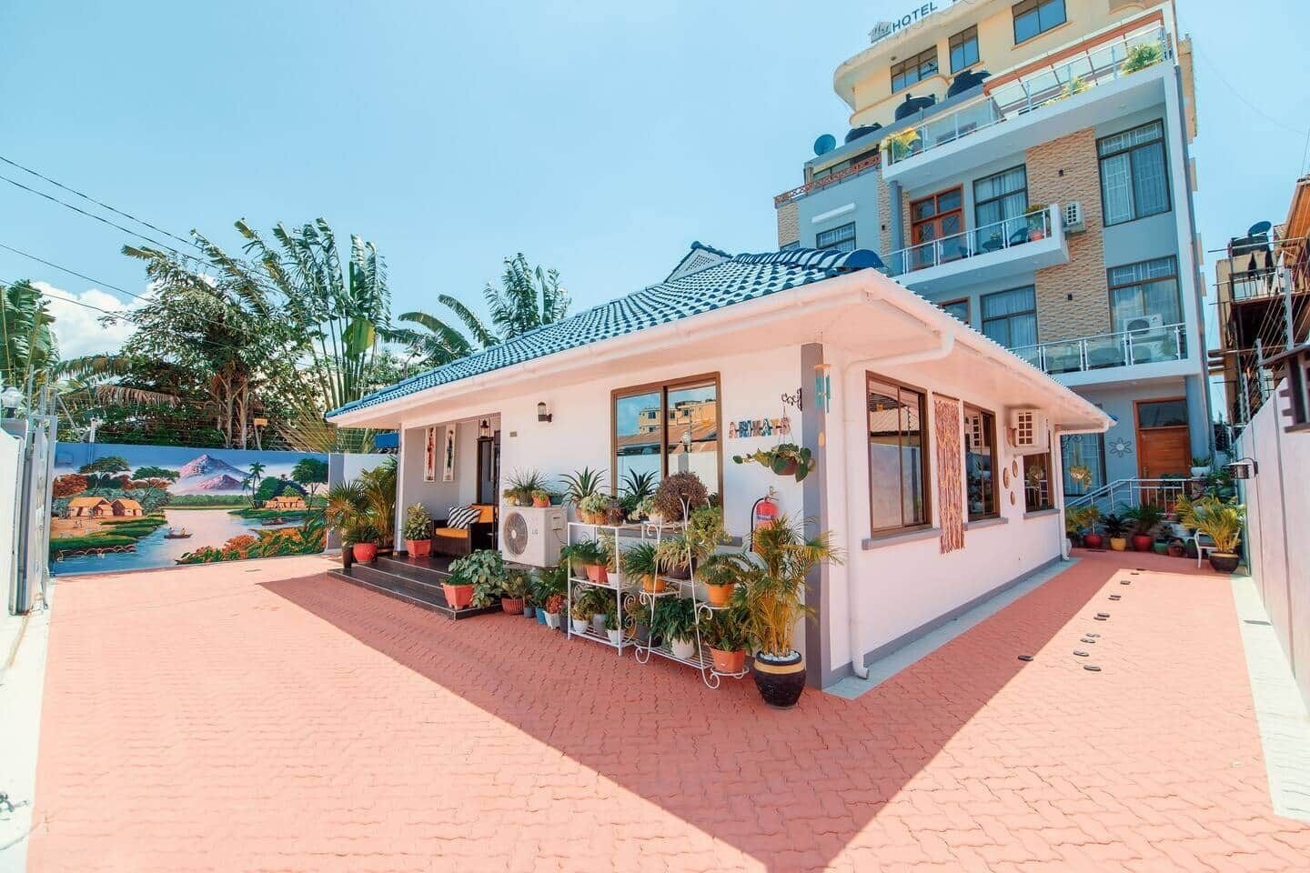 Un hôtel à la façade blanche, doté d’un espace extérieur aménagé et abrité, ainsi que de plantes en pot.