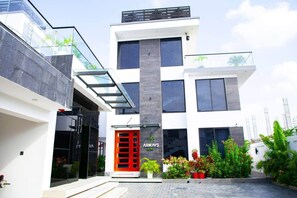 Un edificio moderno de dos pisos con entrada de vidrio, una puerta roja y un letrero que dice 'ARKAYS'.