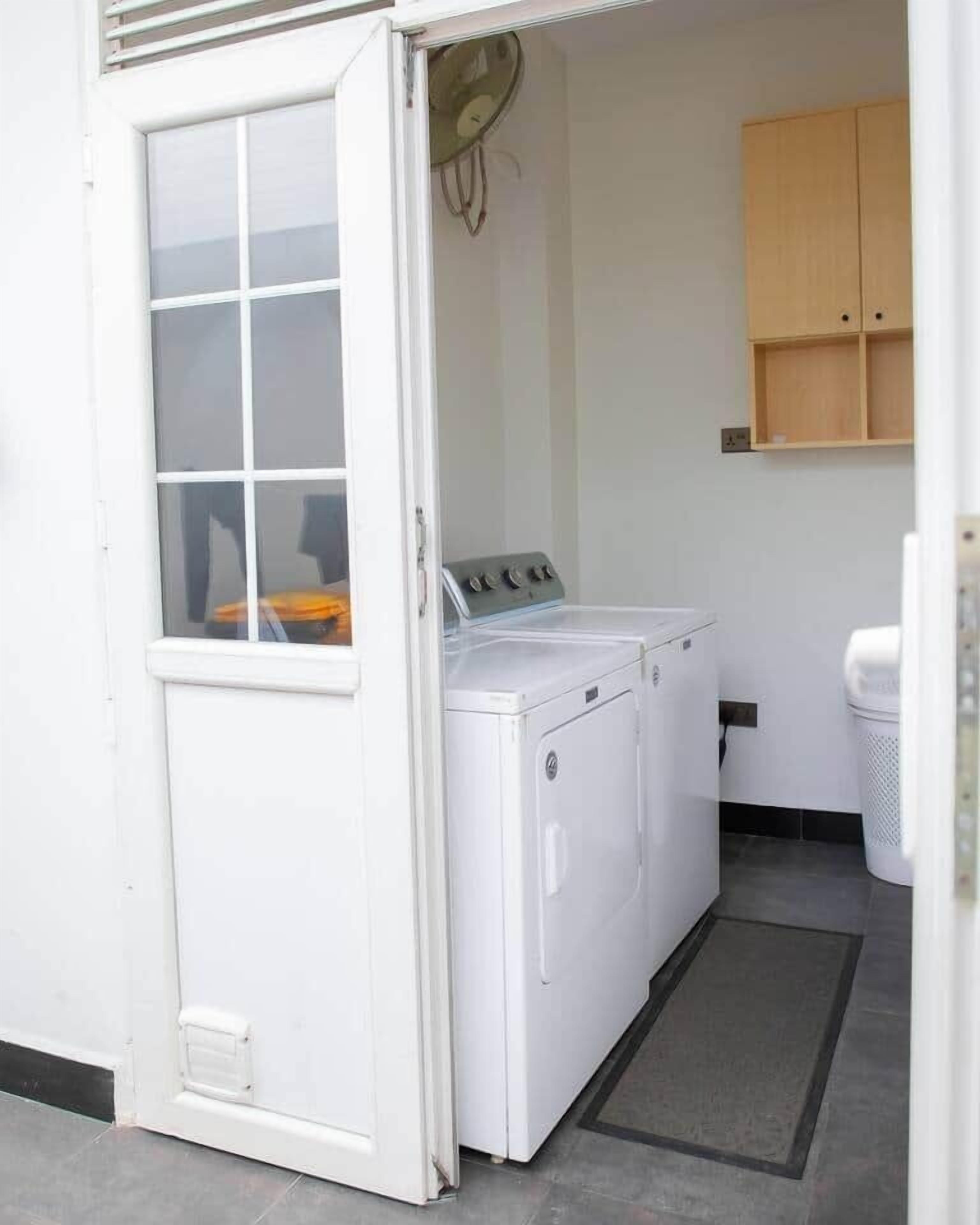 A laundry room with a washing machine, a dryer, and a cabinet.