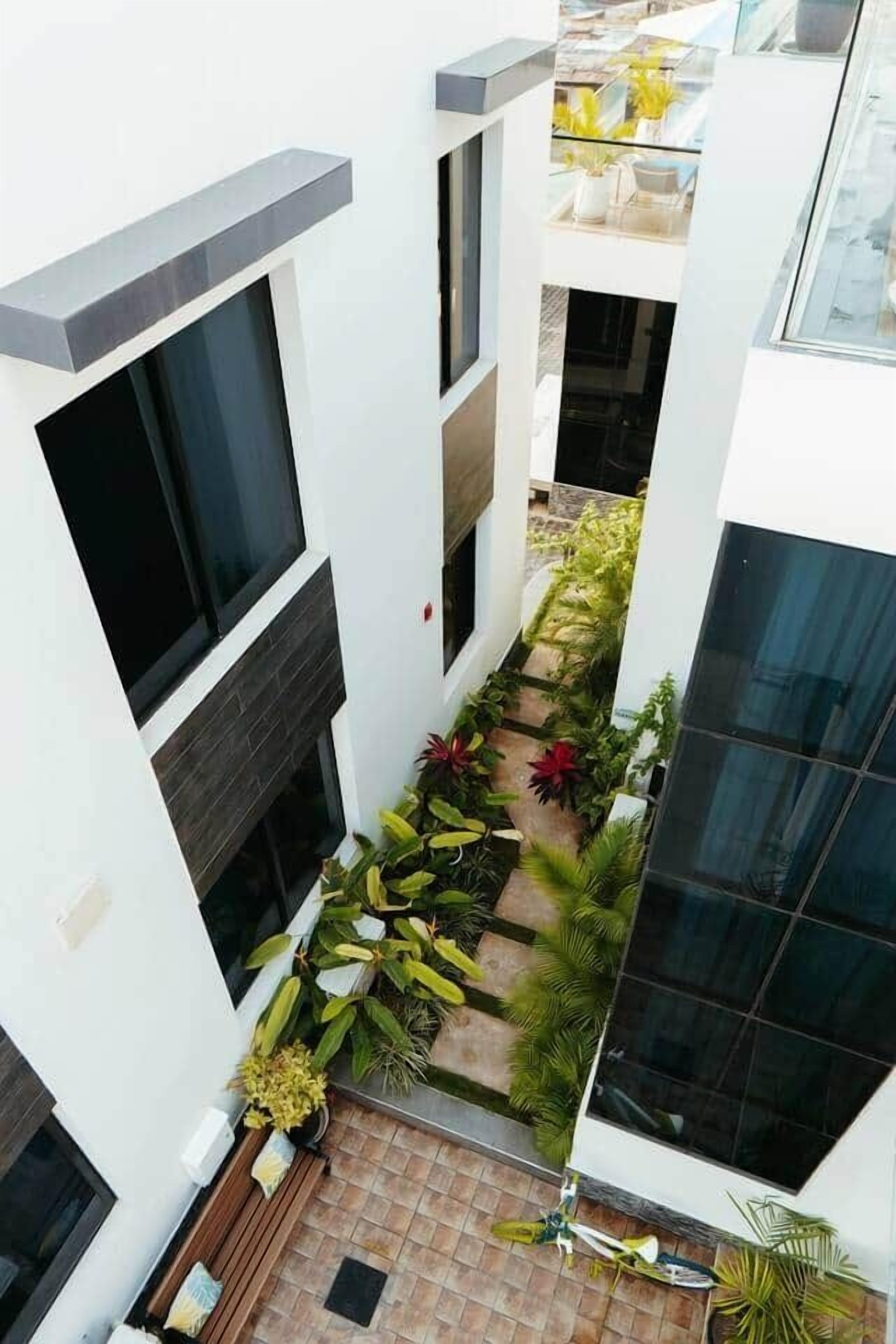 Un edificio moderno con un patio central que presenta una variedad de plantas y un suelo de baldosas.