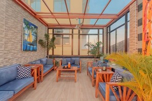 A sunlit indoor space with a glass ceiling, a sofa set, a coffee table, and potted plants. - The Elegant | Spacious Apt | Near shopping (Dar es Salaam)