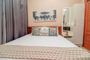 Ein Hotelzimmer mit Bett, Nachttisch, Spiegel und Kleiderschrank.