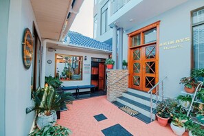 A hotel entrance with a tiled pathway, a bench, and potted plants. - The Lavish suite with Sunset view @Arikays homes (Dar es Salaam)