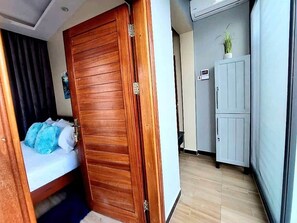 A room with a wooden wardrobe, a bed with blue bedding, and a white cabinet. - The Lavish suite with Sunset view @Arikays homes (Dar es Salaam)