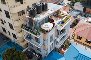 A multi-story building with balconies, a rooftop terrace, and a swimming pool. - The Lavish suite with Sunset view @Arikays homes (Dar es Salaam)