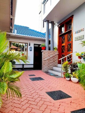 A hotel entrance with a red door, a staircase, and potted plants. - The Retreat - Private Apt - Wi-Fi -Near shopping (Dar es Salaam)