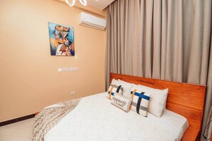 Ein Hotelzimmer mit Bett, einem Bild an der Wand, einer Klimaanlage und einem Vorhang.