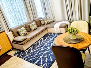 Ein modernes Wohnzimmer mit einer Couch, einem runden Holztisch und einem gemusterten Teppich.
