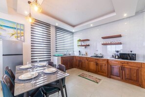 A modern kitchen with a dining area, featuring a built-in oven, microwave, and a stainless steel refrigerator. - Private 1 BDR Apt| w/Pool | Beachwalk - Generator (Jambiani)